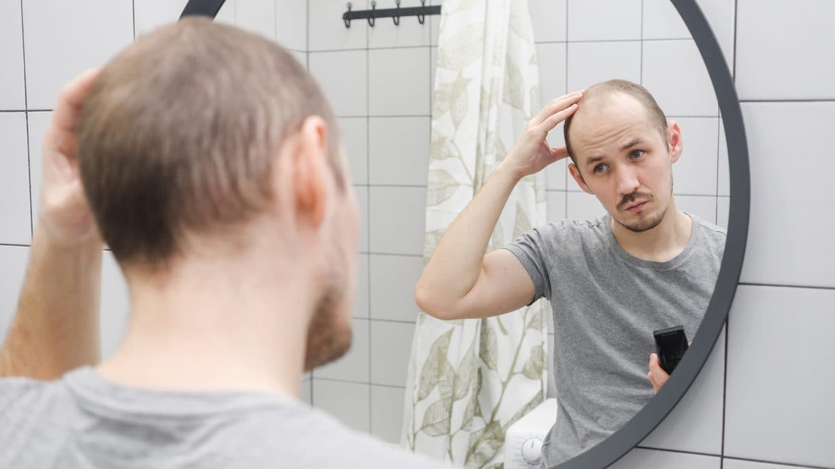 Muž si v zrcadle prohlíží řídnoucí vlasy